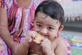 A newborn male toddler trying to bite a biscuit for the first time with his gums