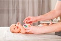 Newborn with paints on a white plaid closeup. Infant holds watercolor rainbow paint and copy space. The concept of the game, care