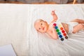 Newborn with paints on a white plaid closeup. Infant holds watercolor rainbow paint and copy space. The concept of the game, care