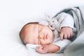 Newborn sleep at first days of life. Portrait of new born baby one week old with cute soft toy in crib in cloth background