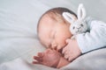 Newborn sleep at first days of life. Portrait of new born baby one week old with cute soft toy in crib in cloth background