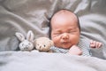 Newborn sleep at first days of life. Portrait of new born baby one week old with cute soft toy in crib in cloth background