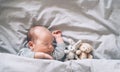 Newborn sleep at first days of life. Portrait of new born baby one week old with cute soft toy in crib in cloth background