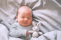 Newborn sleep at first days of life. Portrait of new born baby one week old with cute soft toy in crib in cloth background