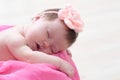 Newborn sleeping in basket with knitted flower on head, baby girl lying on pink blanket, cute child Royalty Free Stock Photo