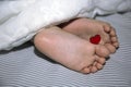 The newborn sleeps under a blanket, legs with a small heart for the holiday