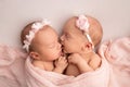 A newborn twins sleeps next to his sister. Newborn twin girls on the background of a pink blanket with pink bandages. Royalty Free Stock Photo