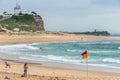 Sandy beach and Nobbys lighthouse at ocean in Newcastle, Australia