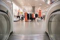 Escalator exit inside a modern department store exiting to ladies fashion clothing department