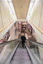 Escalator going down inside a modern department store shop with woman Royalty Free Stock Photo