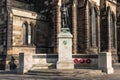 Stone memorial with bronze statue for Northumberland Fusiliers by old church with poppy wreaths laid in rememberance