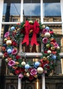 Winter Christmas Yule Wreath on a window with big red bow, flowers and baubles