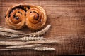 Newly-baked raisin roll bunch of wheat ears on oak Royalty Free Stock Photo