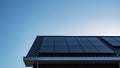 Newly build houses with solar panels attached on the roof against a sunny sky Close up of new building with black solar