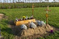 A newly built grave without a tombstone with empty tablets hung on the cross.