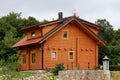 Newly built wooden log cabin house surrounded with uncut grass and lush forest vegetation in background Royalty Free Stock Photo