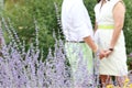 Newly engaged couple holding hands within purple flowers.