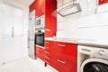 Newly installed bright red open plan kitchen in a room with light laminate flooring and a column of appliances next to a stainless Royalty Free Stock Photo