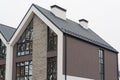 Newly installed construction frame house rain gutter system and chimney pipe on the metal roof top. Big panoramic windows. Royalty Free Stock Photo