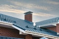 Newly installed construction frame house rain gutter system on the metal roof top. Brick chimney pipe against blue sky. Royalty Free Stock Photo