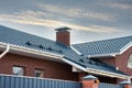 Newly installed construction frame house rain gutter system on the metal roof top. Brick chimney pipe. Automatic metal gates.