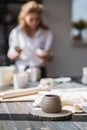 Newly made on a pottery wheel clay pot on a wooden table. Woman paint the ceramic on a background in a pottery studio. Royalty Free Stock Photo