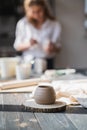 Newly made on a pottery wheel clay pot on a wooden table. Woman paint the ceramic on a background in a pottery studio. Royalty Free Stock Photo