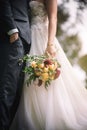 Newly married couple in embrace with the bridge holding a pretty bouquet in a vertical shot Royalty Free Stock Photo