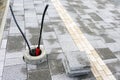 Newly paved sidewalk with guidelines for the visually impaired and a concrete base for a light pole