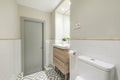 Newly renovated bathroom with a small wooden cabinet with drawers and a white porcelain sink, a mirror integrated into the wall Royalty Free Stock Photo