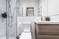 Newly renovated bathroom with small wooden cabinet with drawers and white porcelain sink, shower cabin with glass screen, mirror Royalty Free Stock Photo