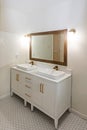 A newly renovated white tiled bathroom with a double sink vanity and gold fixtures Royalty Free Stock Photo