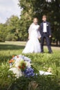 Newly wed holding hands, wedding bouquet in the foreground