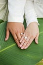 Newly weds putting their hands together on a green leaf.