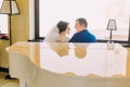 Newlywed bride and groom near the white piano going to kiss. Bright window on background Royalty Free Stock Photo