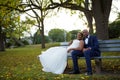 Bride and groom sitting on a park bench at sunset in a colourful scenery Royalty Free Stock Photo