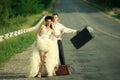 Newlywed couple hitchhiking on a road Royalty Free Stock Photo