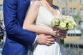 The newlywed couple is holding a beautiful wedding bouquet. Classical wedding photography, symbolizing unity, love and the creati