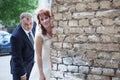 Newlywed couple peek around corner of brick wall, copyspace Royalty Free Stock Photo