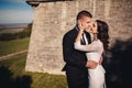 Newlywed couple posing near old castle wall, fairytale wedding at ancient castle outdoors, bride and groom hugging near fortress Royalty Free Stock Photo