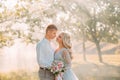 Newlywed couples in the forest and the bright rays of the sun, the groom hugs his dear bride, a girl with blond fair