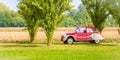 A newlywed unidentifiable couple is driving a retro car on a country road for their honeymoon Royalty Free Stock Photo