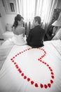 Newlyweds in bedroom with red petals heart. Black and white Royalty Free Stock Photo