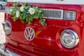 Newlyweds car. Red minibus volkswagen. Retro bus car. Decorated with bouquets of flowers. Festive decor, bridal bouquet