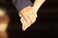 The newlyweds' hands were intertwined, displaying their wedding rings against contrasting attire, symbolising unity and love