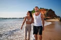 Romantic couple walks on beach at sunset, holding hands. Newlyweds on honeymoon stroll seaside, barefoot in sand. Young Royalty Free Stock Photo