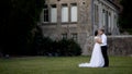 Newlyweds hug on background of manor. Action. Lovely young bride and groom hugging in garden of old mansion. Newlyweds