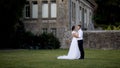 Newlyweds hug on background of manor. Action. Lovely young bride and groom hugging in garden of old mansion. Newlyweds