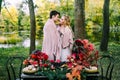 Newlyweds hugging under the plaid next to the festive table. Bride and groom in the park. Autumn wedding. Artwork