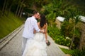 Newlyweds kiss on the alley in the summer, back to the camera